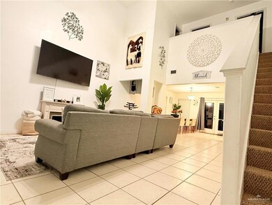 Living area featuring stairs, light tile patterned floors, a towering ceiling, and french doors