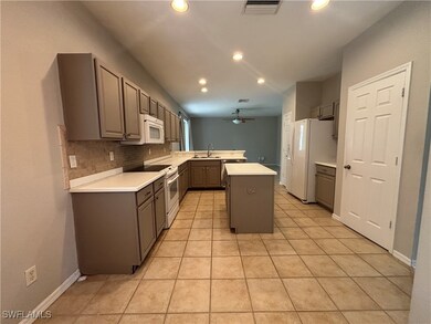 Kitchen with white appliances, ceiling fan, a peni
