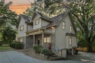 Craftsman house featuring stone siding, roof with shingles, covered porch, and driveway