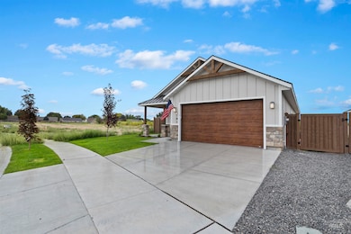 View of front of property featuring a gate, stone siding, driveway, an attached garage, and board and batten siding