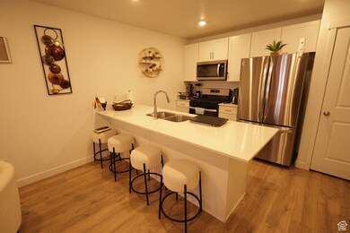 Kitchen with appliances with stainless steel finishes, white cabinets, light wood-style floors, a peninsula, and recessed lighting