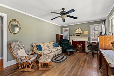 Living area featuring baseboards, a ceiling fan, o