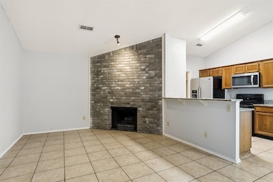 Unfurnished living room with lofted ceiling, a fireplace, and light tile patterned floors