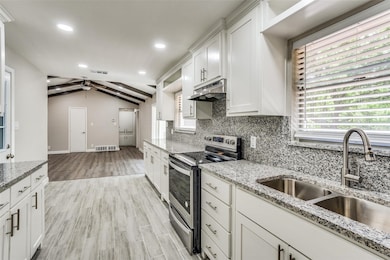 Kitchen featuring stainless steel range with electric stovetop, light wood-style floors, white cabinetry, tasteful backsplash, and light stone counters