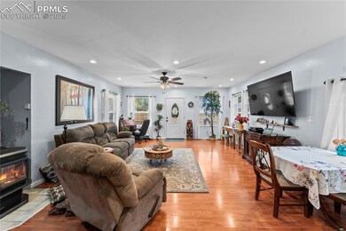 Living area with light wood-style floors, a wood stove, a ceiling fan, and recessed lighting