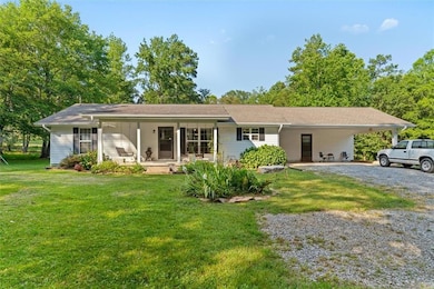 Ranch-style house featuring a porch, driveway, a front lawn, and a carport