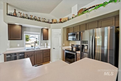 Kitchen with stainless steel appliances, vaulted ceiling, and light countertops