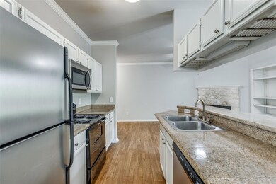 Kitchen featuring stainless steel appliances, ornamental molding, light wood-style flooring, and white cabinets