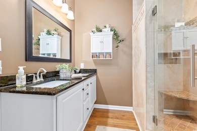 Bathroom with a shower stall, double vanity, baseb