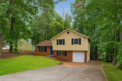 Split level home with brick siding, concrete driveway, a garage, and a front yard
