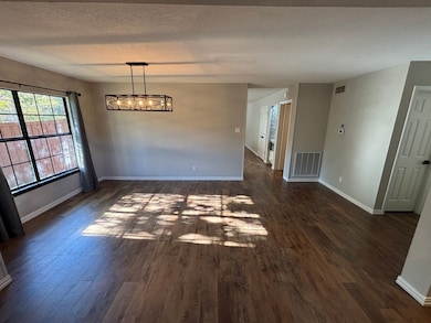 Unfurnished dining area with dark wood finished floors, a textured ceiling, and a chandelier