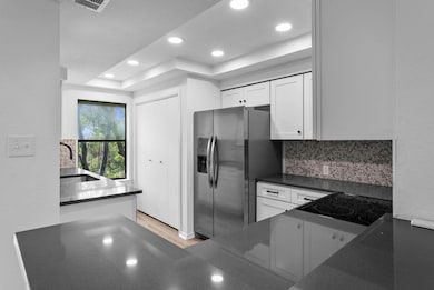 Kitchen featuring dark countertops, a raised ceil