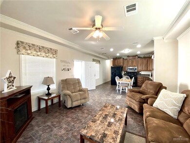 Living room with ornamental molding, a ceiling fan, and dark stone finish flooring