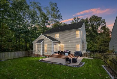 Back house at dusk with a patio area, a deck, and
