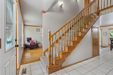Entrance foyer featuring tile patterned flooring, ornamental molding, stairway, and baseboards