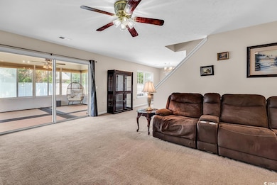 Living area with carpet, ceiling fan, a chandelier