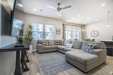 Living room with ceiling fan, recessed lighting, light wood finished floors, and a chandelier