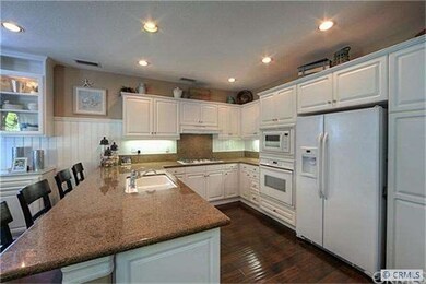 A bright white kitchen with granite surfaces provi