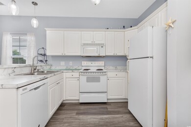 Kitchen with white appliances, light countertops, and decorative light fixtures
