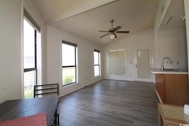 Unfurnished dining area with lofted ceiling, dark wood-style floors, and ceiling fan