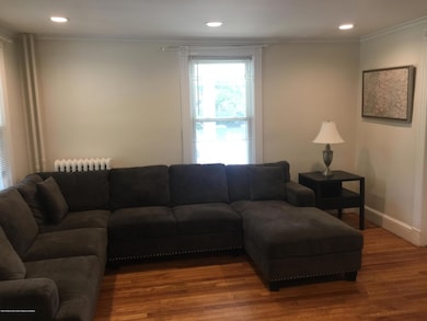 Living room with recessed lights and hardwood floors, high ceilings , abundant natural light .