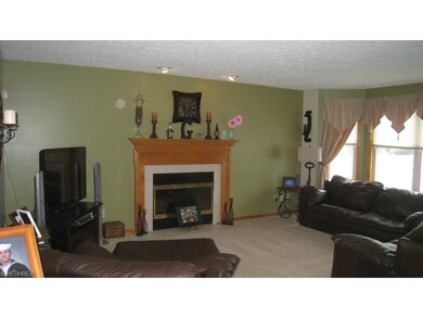 The great room is embellished with a gas fireplace, accent lights and a wall of windows for a view of the fenced back yard and pool.