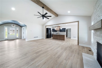 Unfurnished living room featuring a fireplace, a ceiling fan, beam ceiling, arched walkways, and recessed lighting