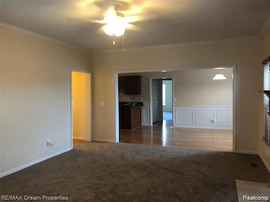 Unfurnished room with light colored carpet, ornamental molding, and ceiling fan