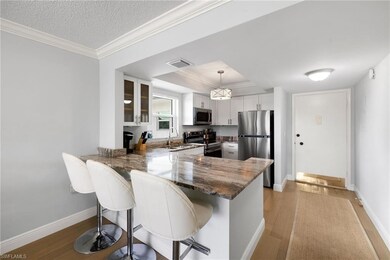 Kitchen featuring appliances with stainless steel finishes, a kitchen breakfast bar, crown molding, glass insert cabinets, and a peninsula