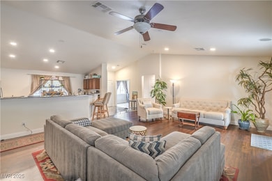 Living area featuring a ceiling fan, wood finished floors, lofted ceiling, and recessed lighting