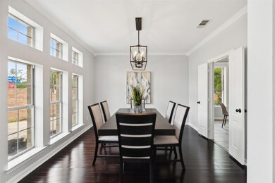 Dining space with dark hardwood / wood-style floors, crown molding, and an inviting chandelier
