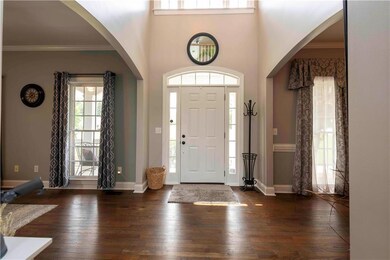 Foyer entrance featuring arched walkways, dark wood-style flooring, and ornamental molding