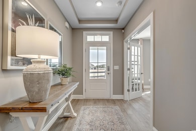 Entrance foyer with a raised ceiling, baseboards, and wood finished floors