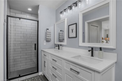 Full bath featuring a stall shower, double vanity, and recessed lighting