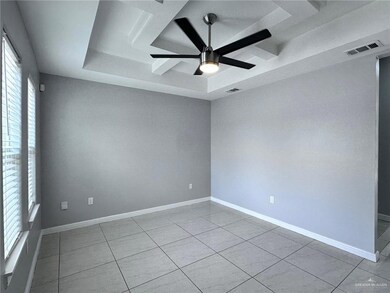 Tiled empty room featuring baseboards, ceiling fan, visible vents, and a raised ceiling