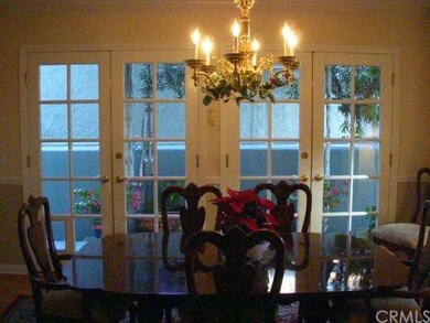 From formal living room to the formal dining room, complete with french doors, wood floor and dramatic chandelier.