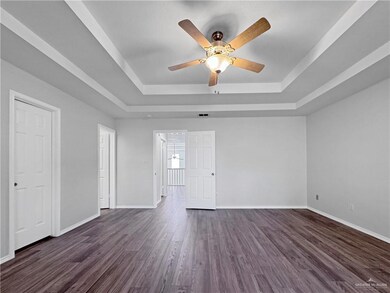 Spare room with dark hardwood / wood-style flooring, a tray ceiling, and ceiling fan
