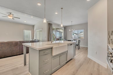 Kitchen featuring an island with sink, gray cabinetry, decorative light fixtures, open floor plan, and recessed lighting