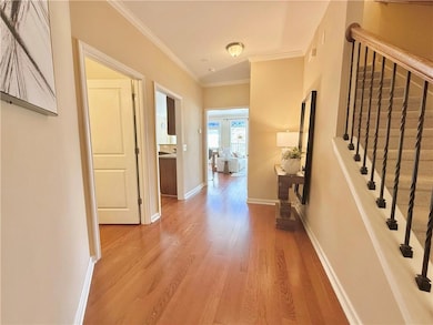 Hall with wood finished floors, baseboards, orname