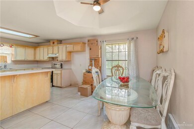 Kitchen with light brown cabinets, ceiling fan, sink, electric stove, and light tile floors