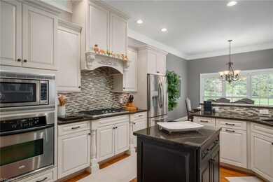 Kitchen with ample custom finished cabinetry, granite countertops, five-burner gas range with lighted hood & center island.