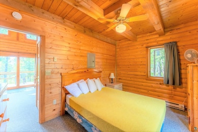 Carpeted bedroom with log walls, beam ceiling, mul