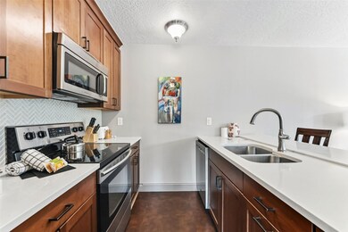 Kitchen featuring appliances with stainless steel finishes, tasteful backsplash, a textured ceiling, light stone counters, and a peninsula