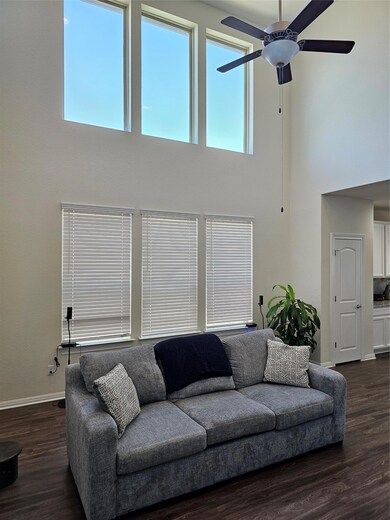 Living area with a towering ceiling, dark wood-style flooring, and a ceiling fan