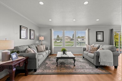 Living room featuring crown molding, light wood finished floors, plenty of natural light, recessed lighting, and a textured ceiling