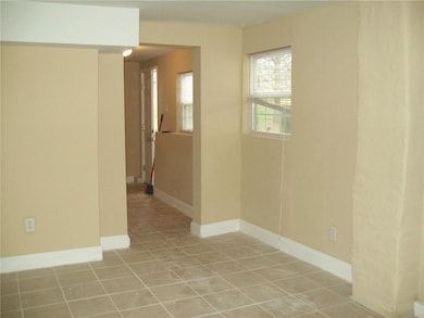 Empty room featuring light tile patterned flooring and baseboards