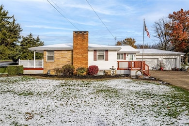 View of snow covered exterior featuring a chimney, a deck, and an outdoor structure
