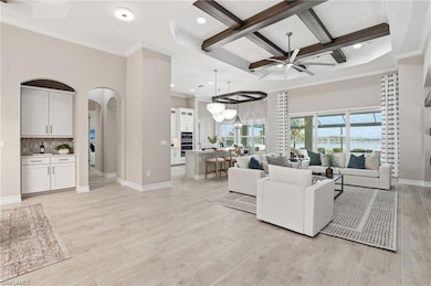Living room featuring ornamental molding, coffered ceiling, a water view, beam ceiling, and a high ceiling