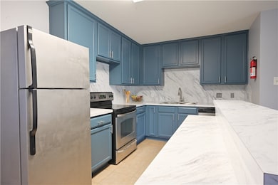 Kitchen featuring blue cabinetry, a sink, stainles