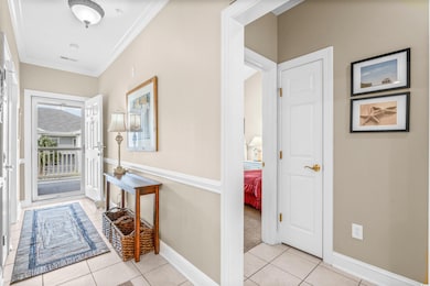 Entrance foyer with light tile patterned flooring and crown molding